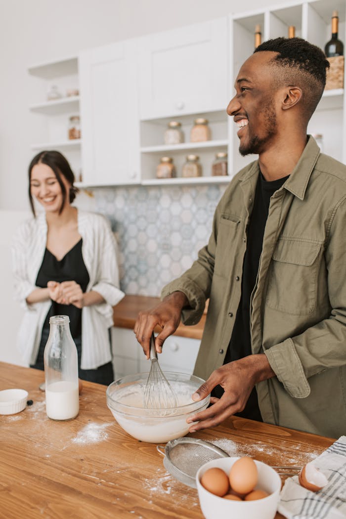Smiling couple baking happily in a modern kitchen setting with flour on the counter.