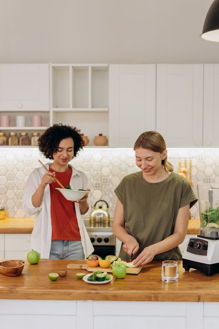 Two women having fun while preparing a healthy meal in a bright, modern kitchen.